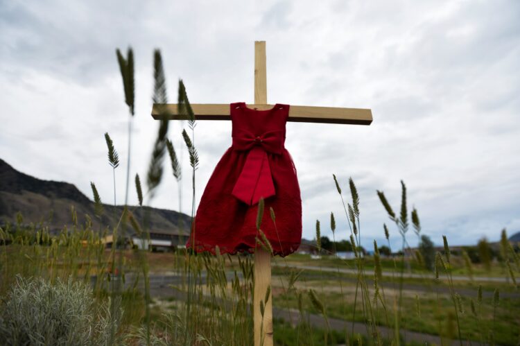 A child's red dress hangs on a stake near the grounds of the former Kamloops Indian Residential School June 6, 2021. The remains of 215 children, some as young as three years old, were found at the site in May in Kamloops, British Columbia. Pope Francis expressed his sorrow at the discovery of the remains at the school, which was run from 1890-1969 by the Missionary Oblates of Mary Immaculate. (CNS photo/Jennifer Gauthier, Reuters)