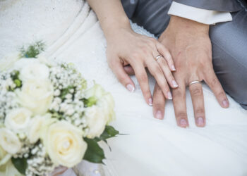hands of a just married couple with the wedding rings and bouquet