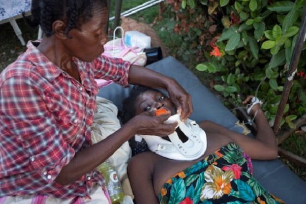 An injured woman is assisted in Les Cayes, Haiti, Aug. 15, 2021, following magnitude 7.2 earthquake the previous day. (CNS photo/Estailove St-Val, Reuters)
