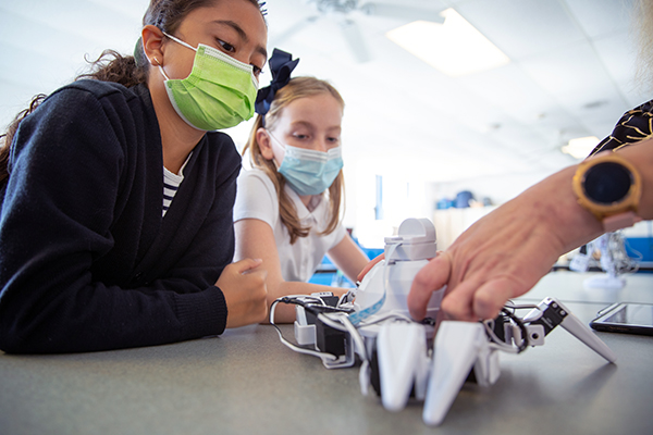 Fifth graders Julieta Gonzalez (left) and Hannah Abelson watch as Principal Carol Spina works on a robot named 'Six' at Our Lady Star of the Sea Regional School in Atlantic City, NJ on Tuesday, September 21, 2021.