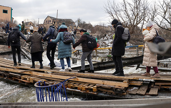 CNS photo/Thomas Peter, Reuters
People fleeing Russian forces use wooden planks to cross the Irpin River March 9 in Ukraine.