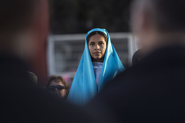 Kenia Salas, playing the part of Mary, looks out into a crowd during a binational "posada" in Nogales, Mexico. The commemoration of Mary and Joseph's search for shelter before the birth of Christ was held by the Kino Border Initiative and Dioceses Without Borders to reflect on the struggles of migrants and migrant families. (CNS photo/Nancy Wiechec) See FAITH-ALIVE-CHRISTMAS-BONUS 45 Nov. 21, 2019.