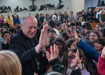 Cardinal Robert W. McElroy of San Diego exchanges high-fives with young members of the parish of St. Frumentius, his titular church in Rome, before formally taking possession of the church and celebrating Mass there April 23, 2023. (CNS photo/Chris Warde-Jones)
