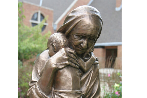 A bronze statue of St. Teresa of Kolkata, cradling a child, is pictured in a file photo overlooking a garden at Our Lady of Lourdes Church in Massapequa Park, N.Y. The statue was donated by the Knights of Columbus. (OSV News photo/CNS file, Gregory A. Shemitz, Long Island Catholic)