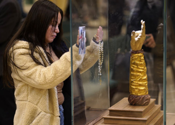 A woman prays in front of at a glass-encased reliquary containing a bone from the arm of St. Jude the Apostle at St. Jude Church in Mastic Beach, N.Y., Nov. 27, 2023. The relic, which arrived in Chicago from Italy in September, is on a nine-month tour of the U.S. (OSV News photo/Gregory A. Shemitz)