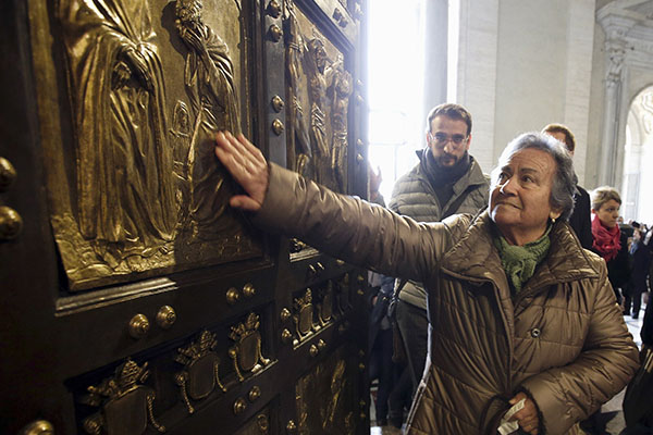 A woman touches the Holy Door in St. Peter's Basilica after Pope Francis opened it to mark the inauguration of the Jubilee Year of Mercy at the Vatican in this Dec. 8, 2015, file photo. Pope Francis has approved the theme "Pilgrims of Hope" to be the motto for the Holy Year 2025. (CNS photo/Max Rossi, Reuters)