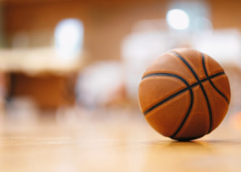 Close-up image of basketball ball over floor in the gym. Orange basketball ball on wooden parquet.
