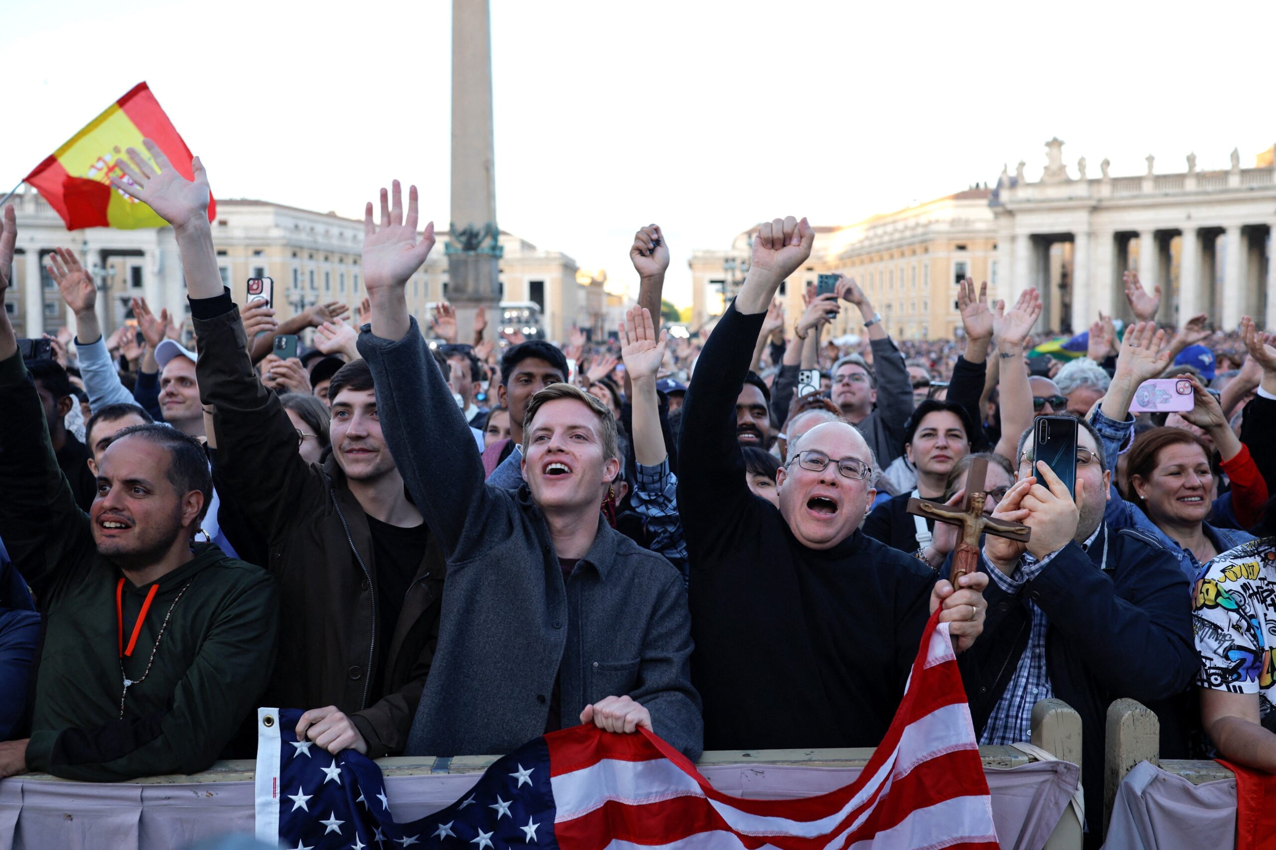 Men holding a U.S. flag cheer as Cardinal Robert Francis Prevost, who has chosen the papal name Leo XIV, appears on the central balcony of St. Peter's Basilica at the Vatican May 8, 2025, following his election during the conclave. He is the first American pope in history. (OSV News photo/Amanda Perobelli, Reuters)