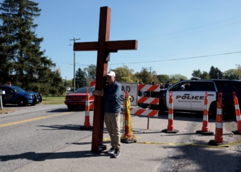 Dan Bradley holds a 10-foot cross near the scene of a mass shooting which took place at the Church of Jesus Christ of Latter-day Saints, in Grand Blanc, Mich., Sept. 29, 2025. (OSV News photo/Rebecca Cook, Reuters)
