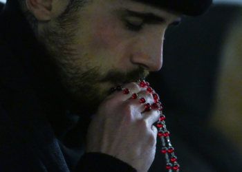 A man kisses a rosary as he joins hundreds of people praying in St. Peter’s Square at the Vatican in this file photo from Feb. 25, 2025. (CNS photo/Lola Gomez)
