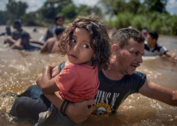 Honduran migrant Luis Acosta carries 5-year-old Angel Jesus through the Suchiate River near Tapachula, Mexico, Oct. 29, 2018. (CNS photo/Adrees Latif, Reuters)