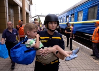 An emergency service worker carries a child as local residents flee via an evacuation train in Pokrovsk, Ukraine, Aug. 22, 2024, as Russian troops advance amid Russia's attack on Ukraine. (OSV News photo/Thomas Peter, Reuters)