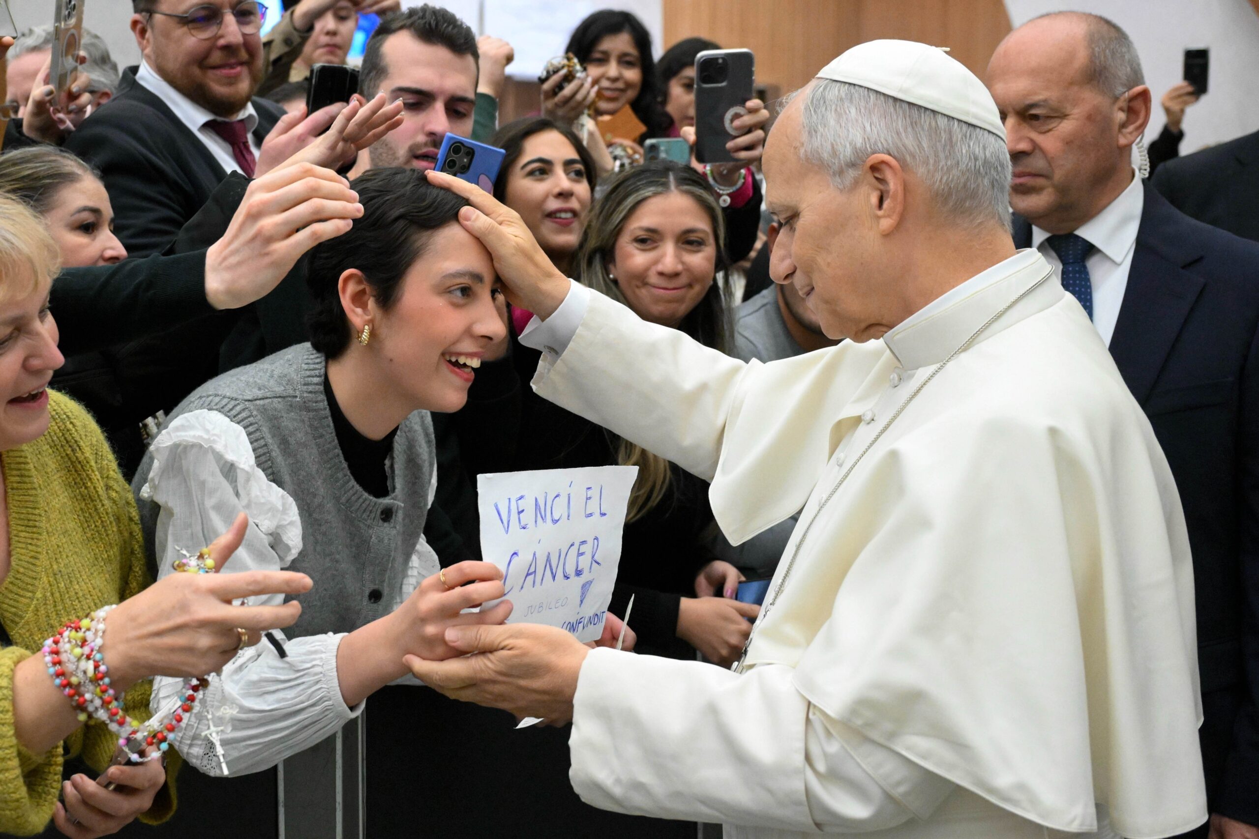 Pope Leo XIV blesses a young woman at the end of his weekly general audience in the Paul VI Audience Hall at the Vatican Jan. 7, 2026. The woman holds a handwritten sign that reads, “Vencí el cáncer” (“I beat cancer”). (CNS photo/Vatican Media)